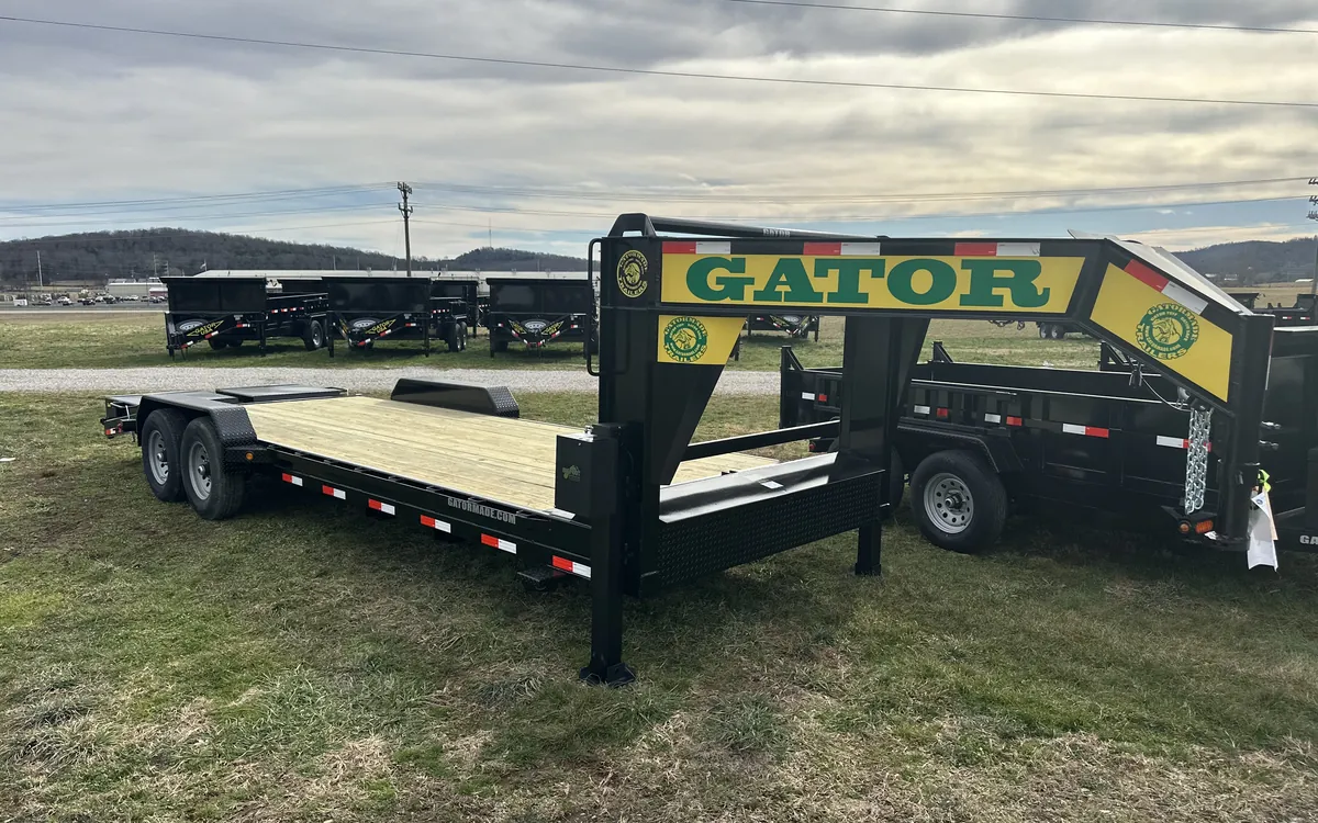 Gatormade gooseneck equipment trailer on the factory lot with a row of dump trailers behind it